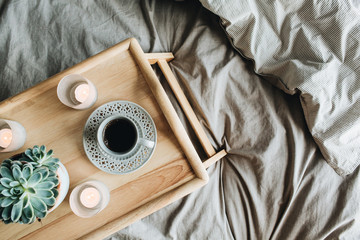 Wall Mural - Morning breakfast in bed with coffee. Flat lay, top view lifestyle still life composition with wooden tray and grey linen.