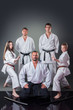 © cirkoglu - Group of young karate players posing with their coach on the gray background