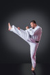 © cirkoglu - Handsome male karate player doing kick on the gray background