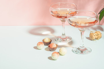 Wall Mural - Champagne or wine in elegant glasses on a pink background bright light. Copy space. Selective focus.