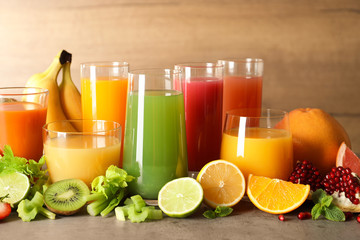 Glasses with different juices and fresh fruits on table