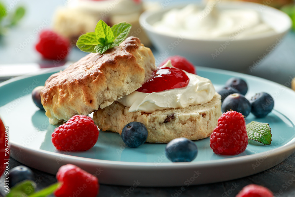 Classic English scones with clotted cream, strawberries jam and other fruit - obrazy, fototapety, plakaty 