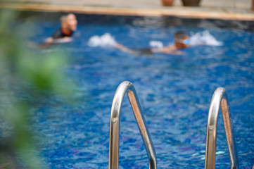 Grab bars ladder in the blue swimming pool