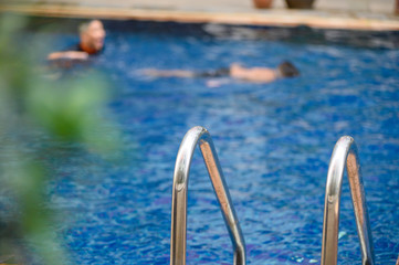 Grab bars ladder in the blue swimming pool