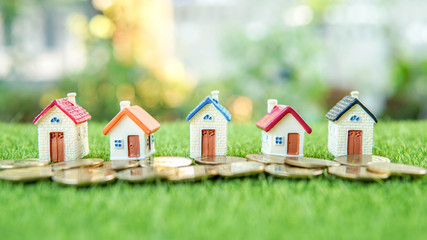 The village of five Little houses on the green field with a ton of coins in front of them