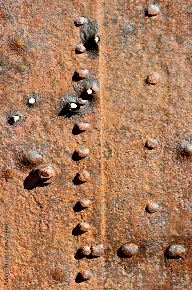 Rusting Metal plates held together by rivets, nut and bolts. Bullet ...