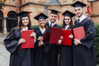 © Тарас Нагирняк - Happy graduation day. 5 graduates hold his graduate  red diplomas in their hands. Future!