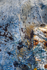 Rough texture in stone, blue, gray, orange, and white, as a nature background