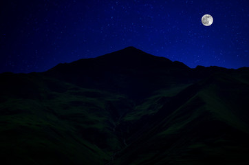 Wall Mural - mountain road through the forest on a full moon night. scenic night landscape of country road at nig