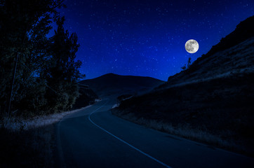 Wall Mural - mountain road through the forest on a full moon night. scenic night landscape of country road at nig