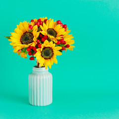 Fotomurales - Bouquet of sunflowers and hypericum berries in mint ceramic vase