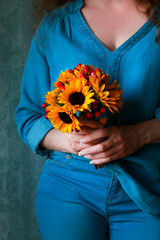 Fotomurales - Woman in blue blouse holding bouquet of sunflowers and hypericum berries.