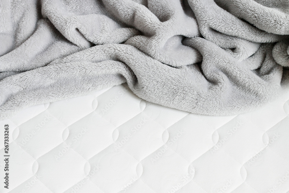 Grey blanket with pompoms on the new mattress. - obrazy, fototapety, plakaty 