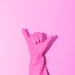 Wall Mural - Fashion creative concept with hand in pink rubber glove, showing gesture. Symbol of Shaka. Aesthetic abstract minimalism.