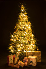 Wall Mural - Gifts and golden Christmas tree bokeh in a black background