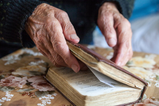 Old woman hands holding the prayer book.
