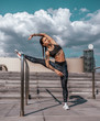 © byswat - Woman athlete girl fitness workout, summer city day morning. Active lifestyle concept warming up jogging. Sportswear leggings top. Tanned skin tattoos. Stretching muscles legs gymnastics, plasticity.