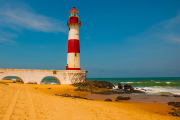 SALVADOR, BAHIA, BRAZIL: Farol De Itapua on the rough sea. Lighthouse on the beach in Sunny weather.