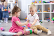 © Oksana Kuzmina - Little toddlers boy and a girl play together in nursery room. Preschool children in day care centre