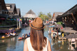 © Kittiphan - Young woman traveler looking at floating market in Thailand, Travel lifestyle concept