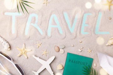 Travel sign on sand background with summer holidays, trip and vacation accessories. Flat lay style.