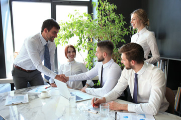 Fototapete - Businessman shaking hands to seal a deal with his partner and colleagues in office.