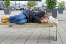 Homeless Woman Sleeping Rough On A Bench