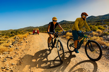 Cycling woman and man riding on bikes in Dolomites mountains andscape. Couple cycling MTB enduro trail track. Outdoor sport activity.