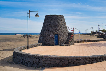 Wall Mural - Tower build og lava stones on Promenade of Playa grande in Puerto del Carmen, Lanztarote, Spain