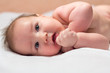 © IrinaBolshunova - Newborn baby lying on its side and smiling on a white sheet and looking up