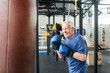 Handsome senior male training with punching bag. Old trainer training with punching bag in fitness studio. People, sport, active way of life.
