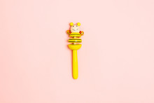 Yellow Wooden Baby Rattle With Bells Over Pink Background. Mock Up. Copy Space. Flat Lay Style