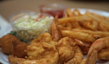 A Fried Shrimp Dinner With French Fries, Cole Slaw And Hush Puppies
