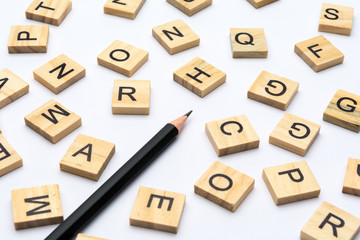 Black pencil and scattered alphabet letters on wooden blocks on white background