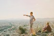 © raisondtre - Couple Man and Woman on top of mountain enjoying beautiful landscape cityscape Athens Greece on background. Tourists relax on hill Athens in summer. Famous Athens city in Europe. traveling adventure.
