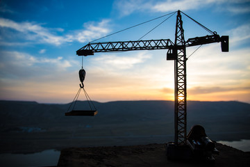 Abstract Industrial background with construction crane silhouette over amazing sunset sky. Tower crane against the evening sky. Industrial skyline