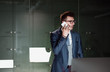 © Halfpoint - A portrait of young businessman with smartphone by lockers in an office.