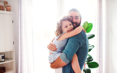 Wall Mural - A small girl with young father at home, hugging
