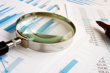 Wall Mural - Magnifying glass for audit and stack of business reports.