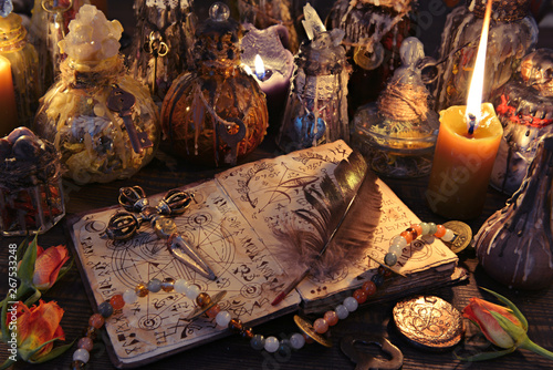 Fotomural Witch book with cross, quill, burning candles and magic bottles on the table