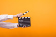 Shot of isolated hands on yellow background holding a clapper