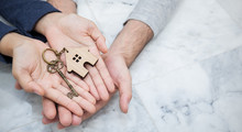 Closeup Real Estate Or Couple Hands Holding And Giving Key House With Copy Space Isolated On Marble Background. Hands Of Man And Woman Buy New House. Together Love Startup New Family Concept Banner