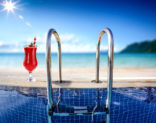 Wall Mural - Fresh cold summer drink of red color. swimming pool background with sea and beach landscape. Summer sunny day. 