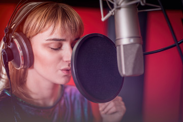 Wall Mural - Pretty female singer recording voice in sound studio