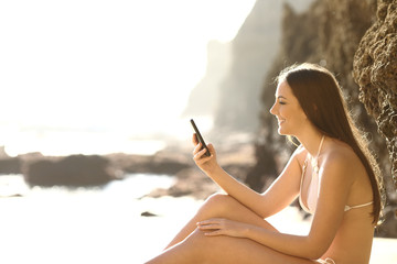 Poster - Happy tourist in bikini checking phone on the beach