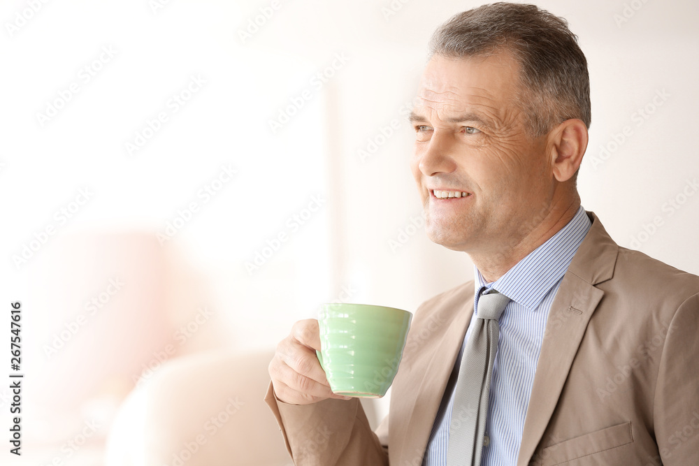 Handsome mature businessman drinking coffee in office