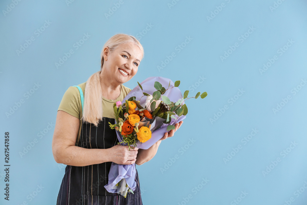 Female florist with bouquet on color background