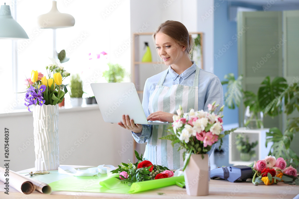 Female florist with laptop in shop