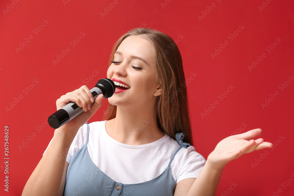 Beautiful female singer with microphone on color background