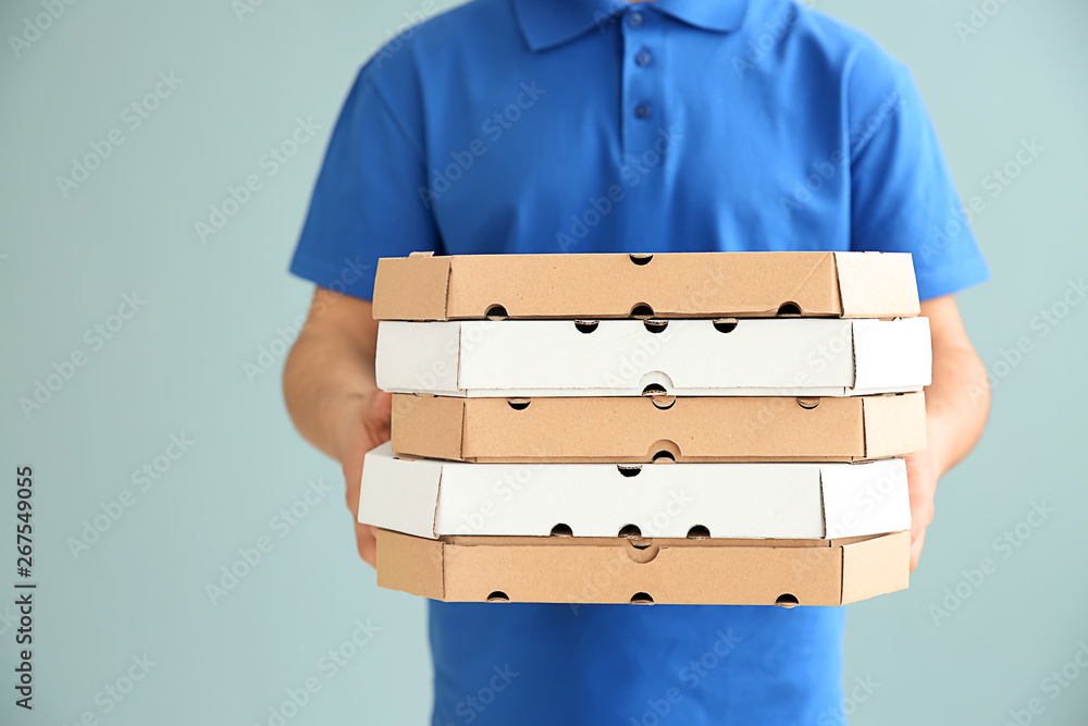 Delivery man with pizza boxes on color background
